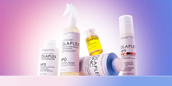 Kolekcja 5 produktów Olaplex do włosów: spray N°0, szampon N°4C, serum N°9, olejek N°7 i kuracja N°3, na tle gradientu.