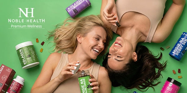 Dwie uśmiechnięte kobiety leżące na zielonym tle, otoczone suplementami Noble Health, w tym kolagenem i żelkami. Widok z góry.