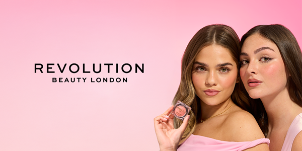 Dwie modelki Revolution Beauty London w różowym tle, jedna prezentuje okrągły róż do policzków. Obie mają makijaż.