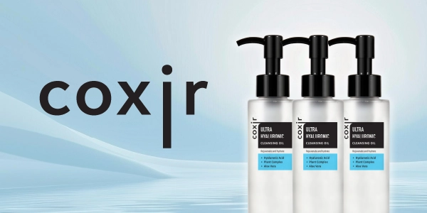 Trzy butelki Coxir Ultra Hyaluronic Cleansing Oil, przezroczyste z czarnymi pompkami i niebieskimi etykietami, na błękitnym tle.