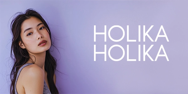 Modelka z długimi, ciemnymi włosami i delikatnym makijażem na fioletowym tle, banner marki HOLIKA HOLIKA.