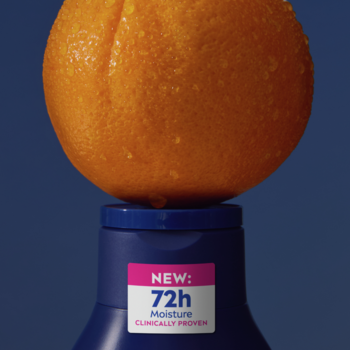 Nivea Q10 + witamina C mleczko 72h. Ciemnoniebieska butelka z pomarańczą na korku, zbliżenie.