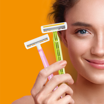 Dwie jednorazowe golarki BIC Pure Lady, różowa i zielona, trzymane przed uśmiechniętą kobietą na pomarańczowym tle.