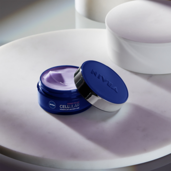 Zbliżenie na otwarty słoiczek kremu NIVEA CELLULAR FILLER na noc, granatowy, z widocznym fioletowym kremem.