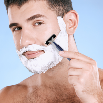 Mężczyzna goli się maszynką BIC Flex 3 Classic z 3 ruchomymi ostrzami, pokryty pianką, na błękitnym tle.