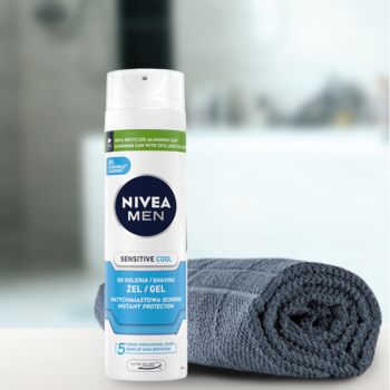 Biały NIVEA MEN Sensitive Cool żel do golenia, tuba z niebieskim logo, na blacie obok szarego ręcznika.