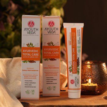 Naturalna pasta do zębów Ayouth Veda Ayurvedic Total Care, tubka i dwa biało-pomarańczowe opakowania na drewnie.