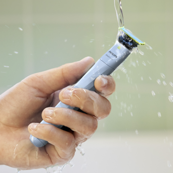 Ręka trzyma szare ostrze Philips OneBlade pod bieżącą wodą, podkreślając jego wodoodporność i łatwość czyszczenia.