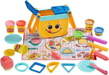 Play-Doh Piknikowa Zabawa, wiaderko z uśmiechem, foremki, narzędzia i różnokolorowa masa plastyczna na kocu.