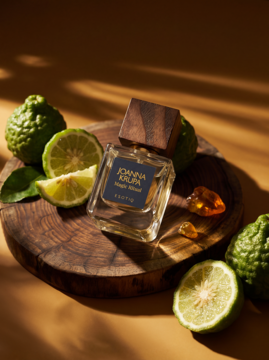 Joanna Krupa Magic Ritual woda perfumowana, butelka z drewnianym korkiem na drewnie, obok bergamotki i ambra.