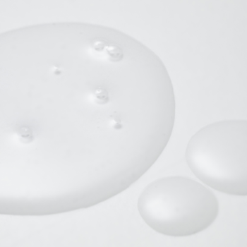 Zbliżenie na trzy przezroczyste, żelowe krople Centella Unscented Serum z bąbelkami na białym tle.