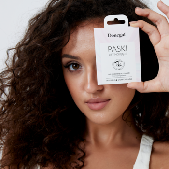 Kobieta prezentuje różowe opakowanie Donegal Paski Liftingujące na opadające powieki, trzymając je przed okiem.