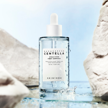 Skin1004 Madagascar Centella Hyalu-Cica First Ampoule, nawilżająca ampułka w butelce, na tle skał i rozprysków wody.