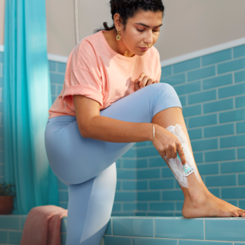 Kobieta goli nogę maszynką Gillette Venus 3 Sensitive dla wrażliwej skóry. Widoczna piana do golenia.
