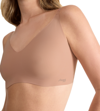 Kobieta w brązowej braletce Sloggi z miękkiej mikrofibry, gładkiej, bez fiszbin. Widok z boku.