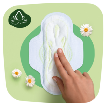 Podpaska Naturella Classic Normal ze skrzydełkami, dotykana dłonią, na zielonym tle z rumiankami.