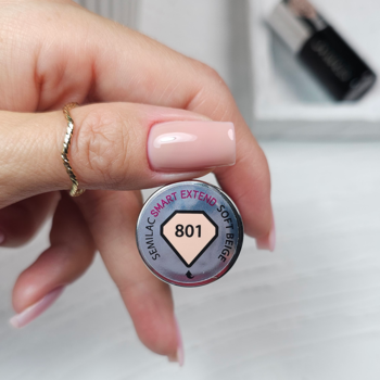 Dłoń z pierścionkiem trzyma lakier hybrydowy Semilac Smart Extend 801 Soft Beige. Widoczne pomalowane paznokcie.