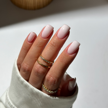 Zbliżenie na dłoń z hybrydowym lakierem Semilac Smart Extend nr 806 ombre, błyszczące paznokcie i złote pierścionki.