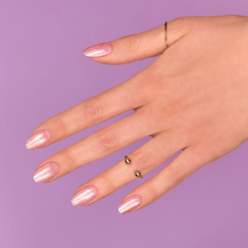 Dłoń z paznokciami w perłowo-różowym, lśniącym lakierze Semilac Spark of Bare Love na fioletowym tle.