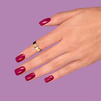 Zbliżenie na dłoń ze złotym pierścionkiem i burgundowo-brązowym lakierem Semilac 404 Black Beans Muffin na fioletowym tle.