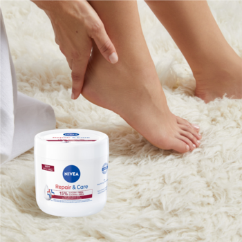 NIVEA Repair & Care krem multifunkcyjny Urea 400ml, biały słoik, w tle stopy na puszystym dywanie.