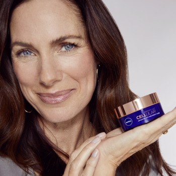 Uśmiechnięta kobieta trzyma ciemny słoiczek kremu NIVEA CELLULAR EXPERT LIFT przeciw zmarszczkom.