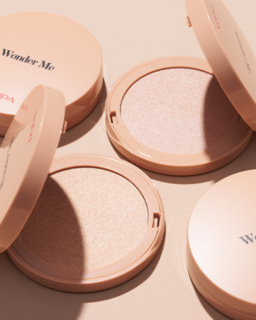 Trzy kompaktowe rozświetlacze Pupa Wonder Me Glow 101 Rose Gold, dwa otwarte, ukazujące jedwabisty puder, na jasnym tle.