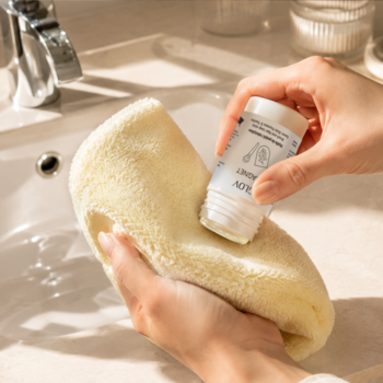 Mydełko Glov Magnet Cleanser do mycia akcesoriów, białe, w dłoniach czyści żółtą rękawicę GLOV nad umywalką.