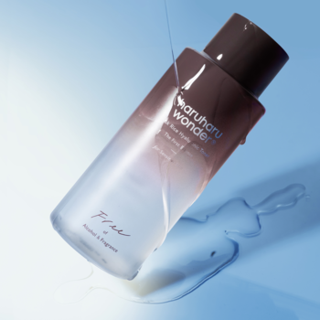 Haruharu Wonder Black Rice Hyaluronic Toner dla skóry wrażliwej, matowa butelka, strumień płynu na błękitnym tle.