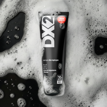 Czarna tuba szamponu DX2 przeciw wypadaniu włosów z białym logo i czerwoną etykietą, widok z góry w pianie.