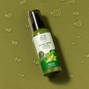 Olej do włosów Petal Fresh Ultra-Shine z awokado do suchych włosów, zielona butelka na zielonym tle z kroplami.