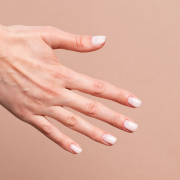 Dłoń z naturalnym manicure, paznokcie pokryte półtransparentną bazą Semilac Skin Tone Cover Base w odcieniu mlecznym.