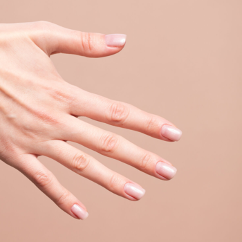 Dłoń z naturalnym, eleganckim manicure. Paznokcie pokryte półtransparentną bazą Semilac Skin Tone Cover Base, beżowo-różowe.