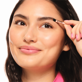 Zbliżenie na kobietę aplikującą Essence Brow Powder Duo Medium do brwi, używając dołączonego pędzelka.
