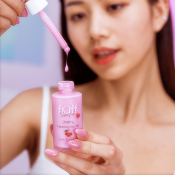 Kobieta trzyma różowe mleczko rozświetlające Fluff Cherry z pipetą, z której kapie płyn do butelki.