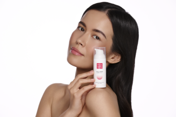 Kobieta z promienną cerą trzyma krem Hada Labo Hyalu Renew z kwasem hialuronowym w białej butelce z pompką.