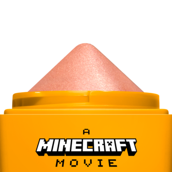 NYX Rare Highlight Balm A Minecraft Movie: zbliżenie na otwarty pomarańczowy sztyft z brzoskwiniowym rozświetlaczem.