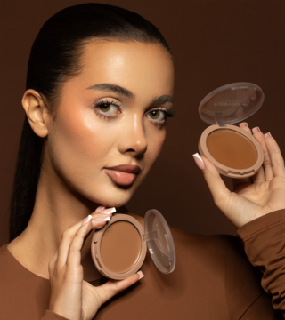 Kobieta prezentuje dwa otwarte kremowe bronzery Everybody London x Aleksandra Sosfa Light. Jasny odcień produktu.