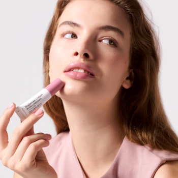 Kobieta aplikuje peptydowy balsam do ust Your Kaya Smoky Rose. Mała, jasnoróżowa tubka przy ustach, widok z bliska.