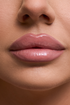 Zbliżenie na usta z błyszczykiem Dessi Creamy Cover Lip Tint Candy. Pełne, błyszczące usta w naturalnym odcieniu nude.