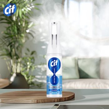 Cif Infinite+ Clean, biała butelka sprayu z ergonomicznym rozpylaczem, na blacie w tle jasnego salonu.