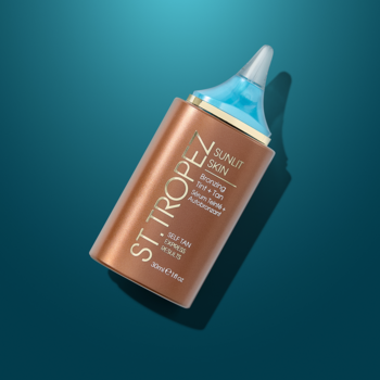 St. Tropez Sunlit Skin Bronzing Tint + Tan, brązowe serum z kwasem hialuronowym, butelka z niebieskim aplikatorem, widok z ukosa.