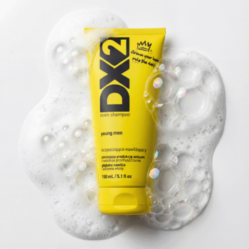 DX2 Young Men szampon oczyszczająco-nawilżający w żółtej tubce, otoczony białą pianą, widok z góry.