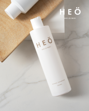 Biała butelka nawilżającego szamponu Heö Helsinki Hydra 250ml, na marmurze, widok z góry, logo w rogu.