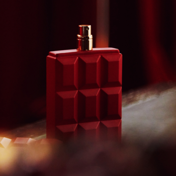 Czerwony flakon perfum Sabrina Carpenter Cherry Baby z wypukłym wzorem czekolady, złota nakrętka, widok z boku.