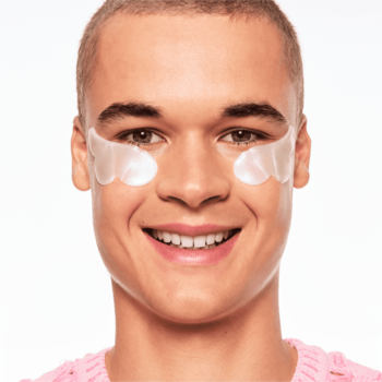 Uśmiechnięty mężczyzna z perłowymi, sercowatymi Essence Hydro Gel Eye Patches pod oczami.