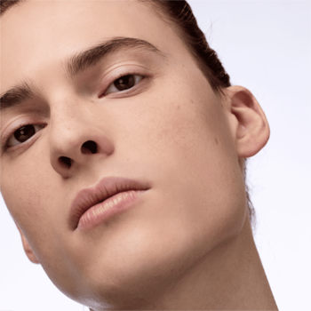 Zbliżenie twarzy modela z nieskazitelną, matową cerą, efekt pudru Catrice Magic Shine Eraser.