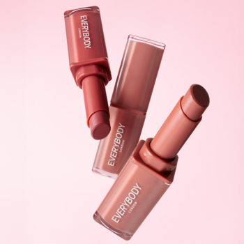 Trzy szminki Plumping Lipstick Everybody London w barwach nude, beżu i cynamonu, uniesione na różowym tle.
