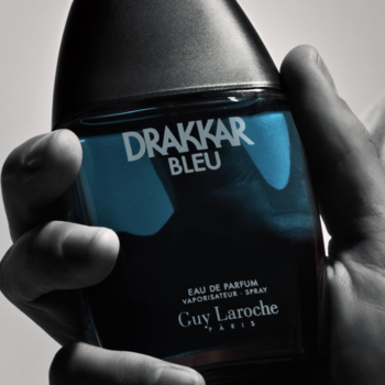 Męska woda perfumowana Guy Laroche Drakkar Bleu, czarno-niebieska butelka z białym napisem, trzymana w dłoni.