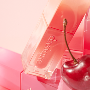 Dasique Juicy Dewy błyszczyk nawilżający Pink Guava w przezroczystej butelce, widoczny napis, obok świeża wiśnia.